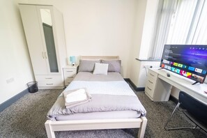 A hotel room with a bed, a desk with a computer, a wardrobe, and a window with blinds. - Stunning Studio in Birmingham (Birmingham)