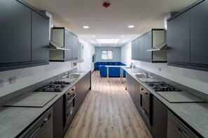 A modern kitchen with grey cabinets, a central island, and a blue sofa in the background. - Stunning Studio in Birmingham (Birmingham)
