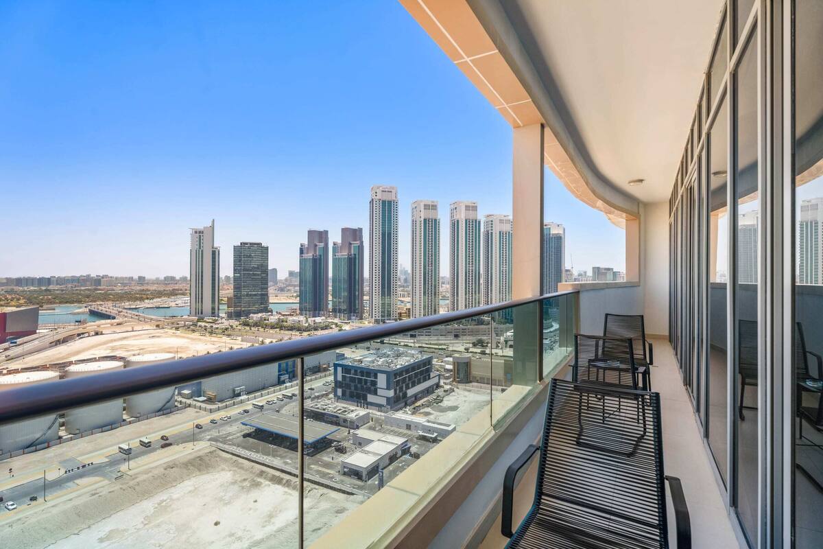 Un balcon offrant une vue sur le paysage urbain, avec notamment des immeubles de grande hauteur et un chantier de construction.