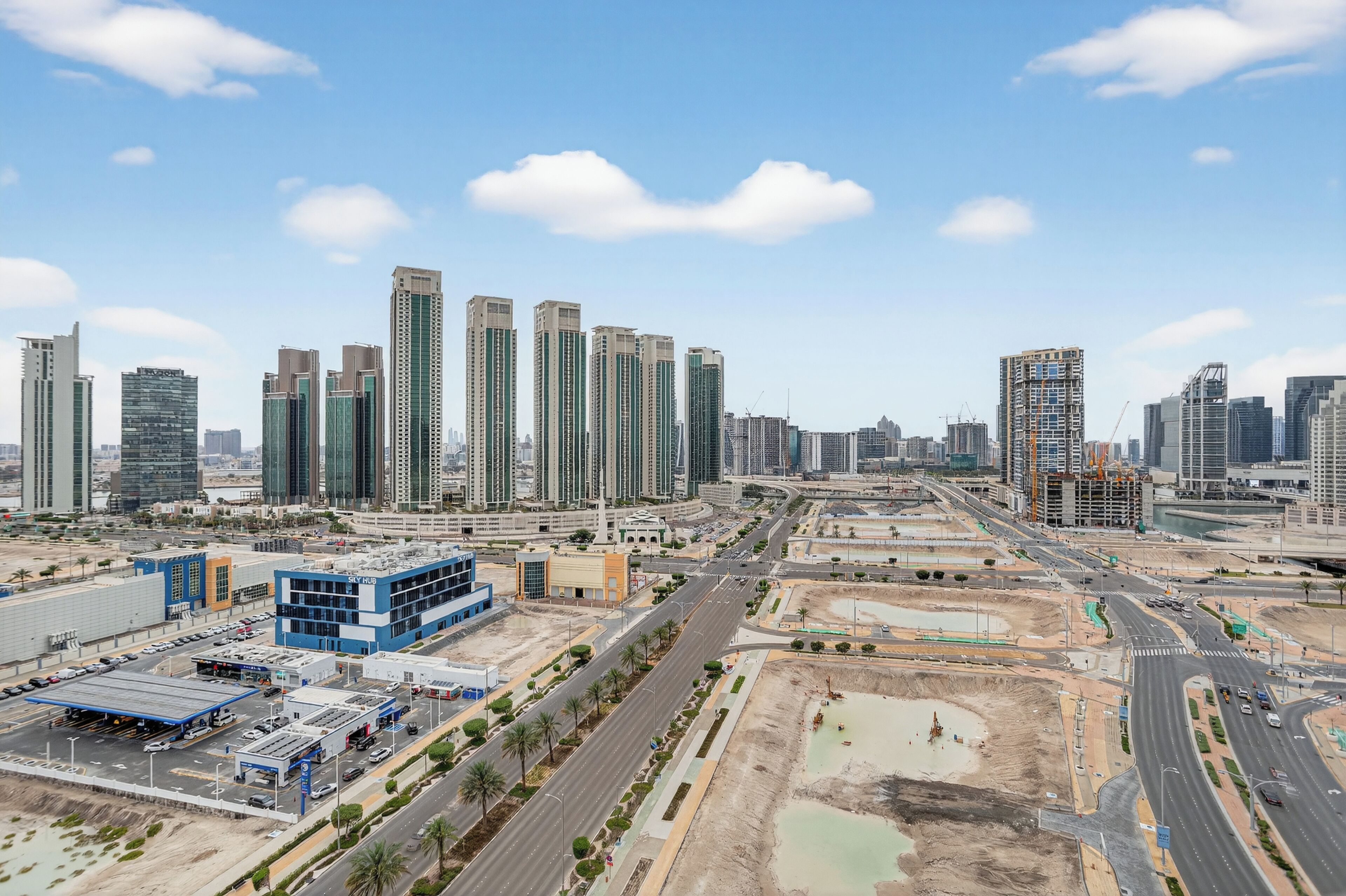 A cityscape with high-rise buildings, a highway, and a parking area.