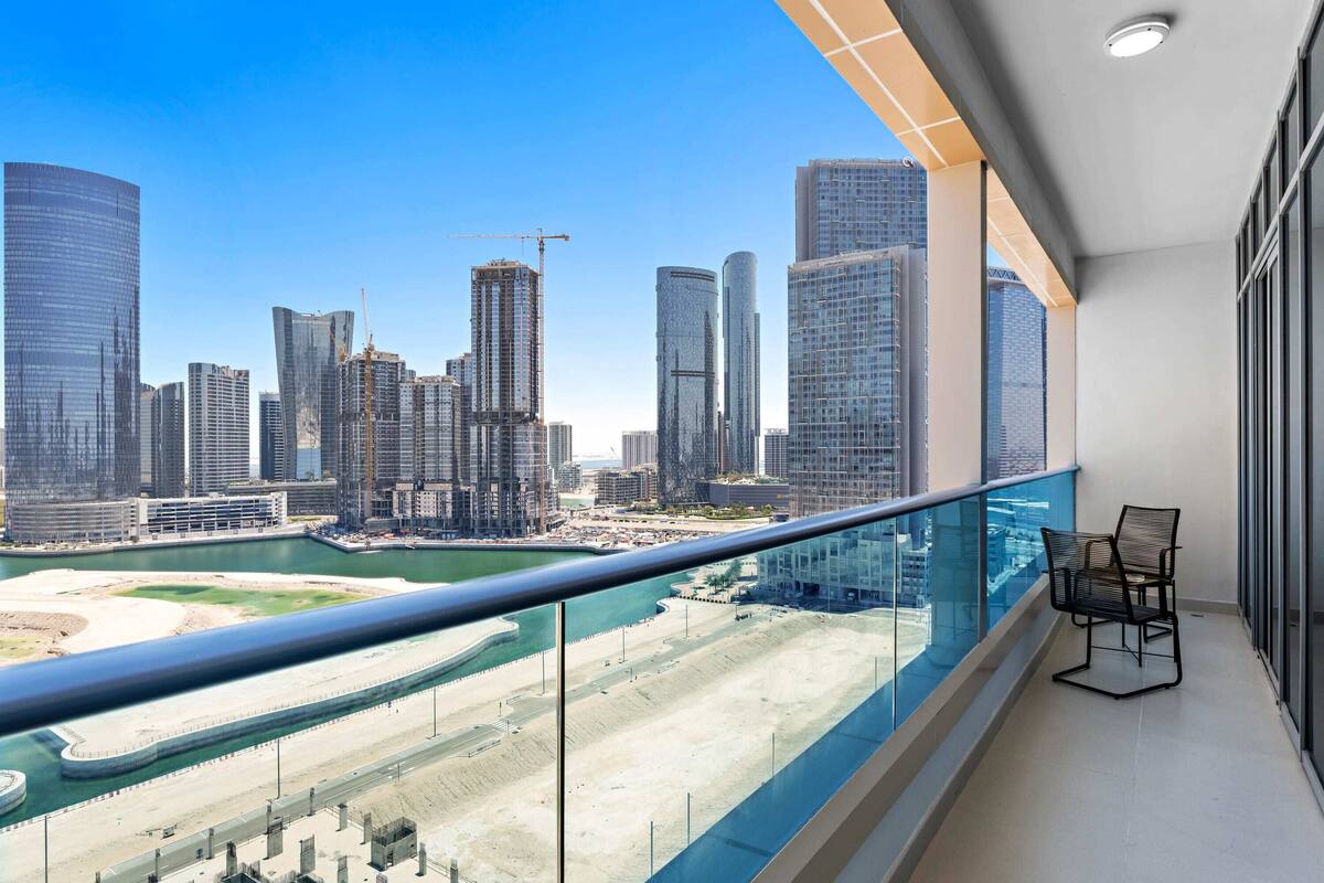Un balcon offrant une vue sur le paysage urbain, avec notamment des immeubles de grande hauteur et un port de plaisance.