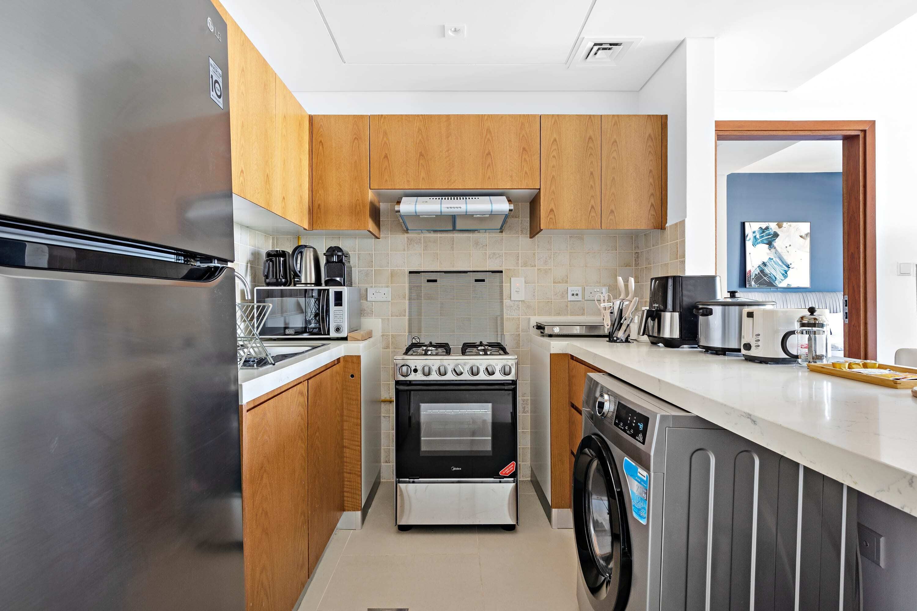 Une cuisine moderne avec des meubles en bois, des appareils électroménagers en acier inoxydable et un four encastré.