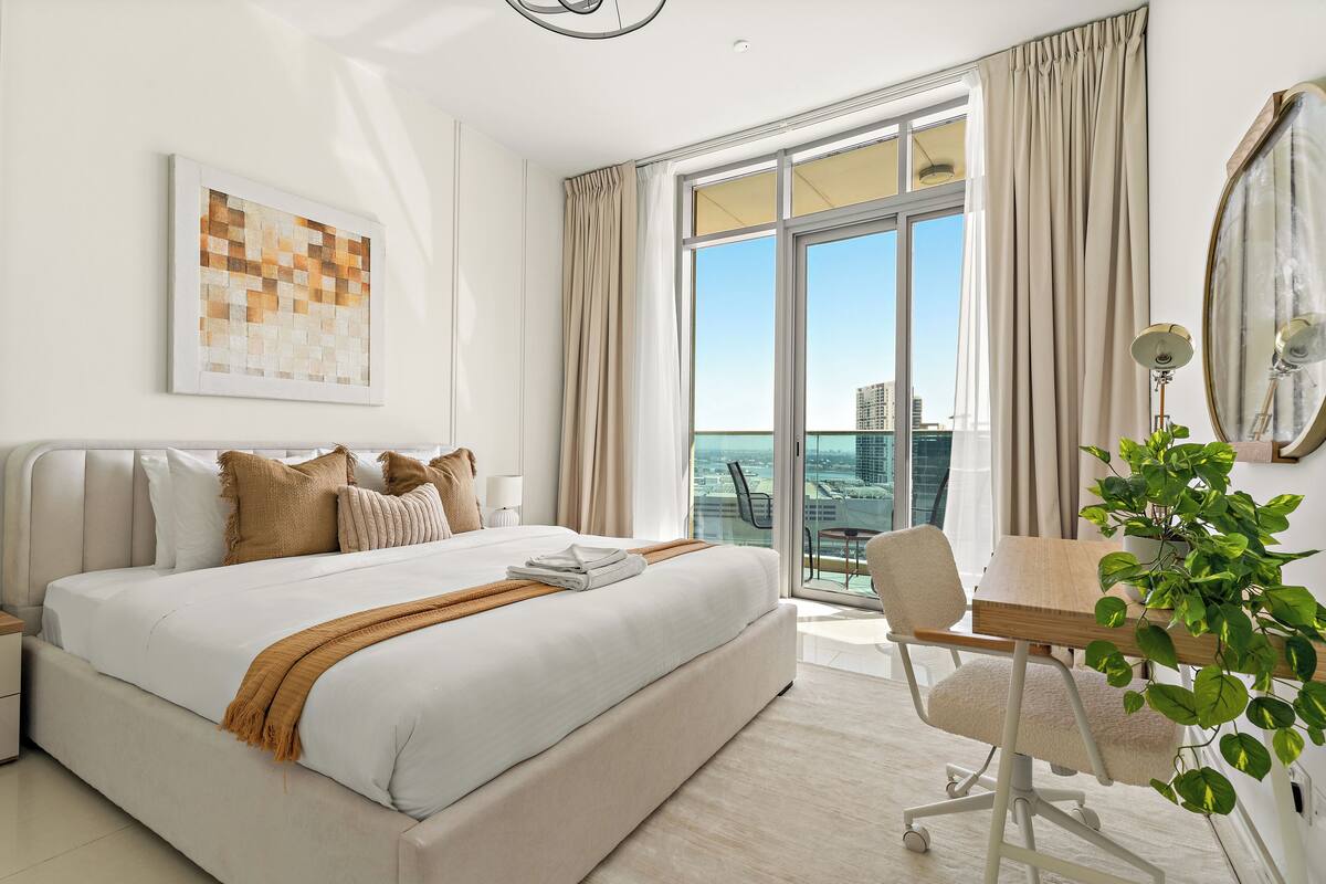 Une chambre d’hôtel moderne avec un grand lit, un bureau et une vue sur la ville.