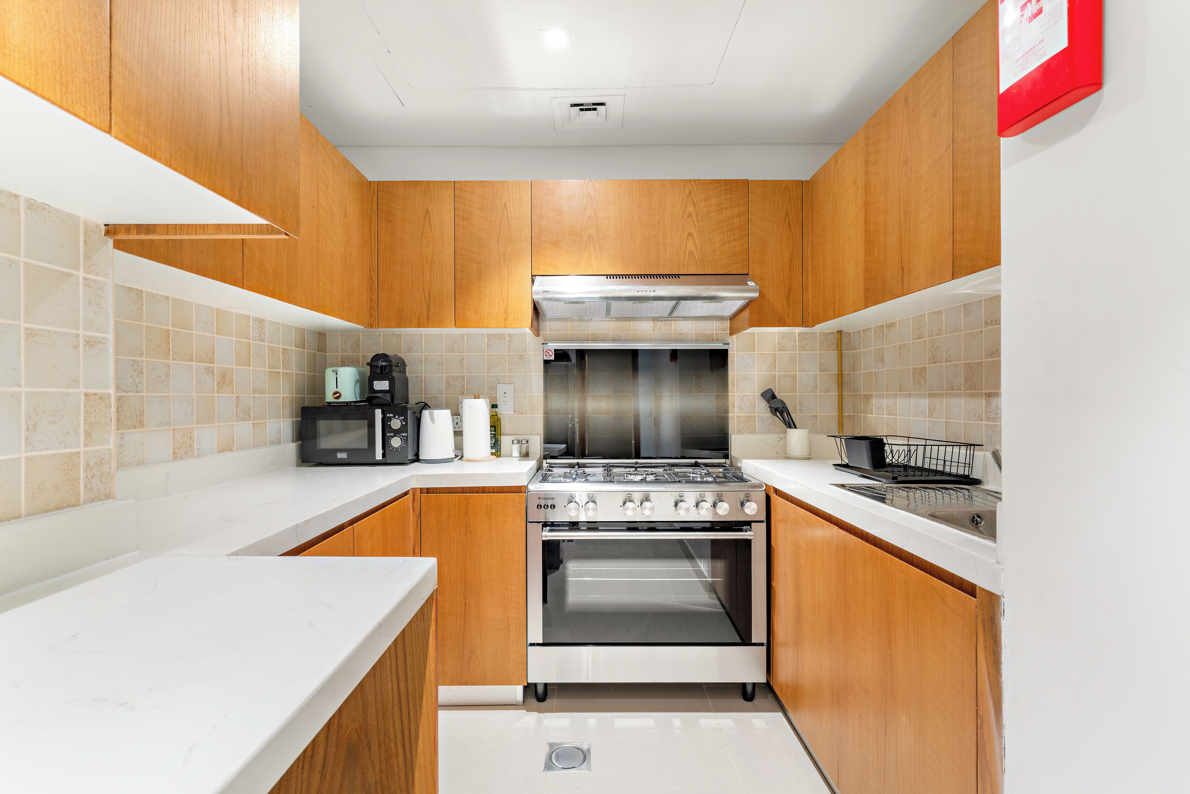 A compact kitchen with wooden cabinets, a built-in oven, and a microwave.