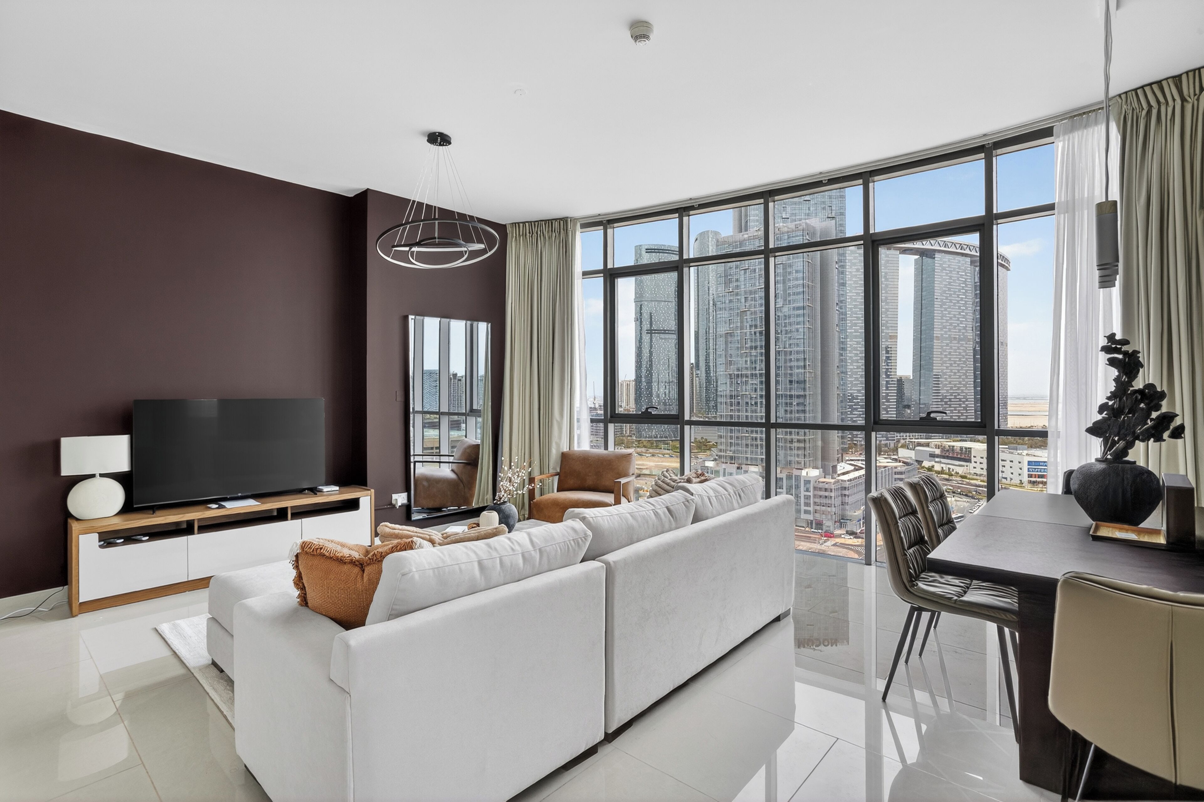 A modern living room with a large window, a flat-screen TV, a sofa, a dining table, and a chair.