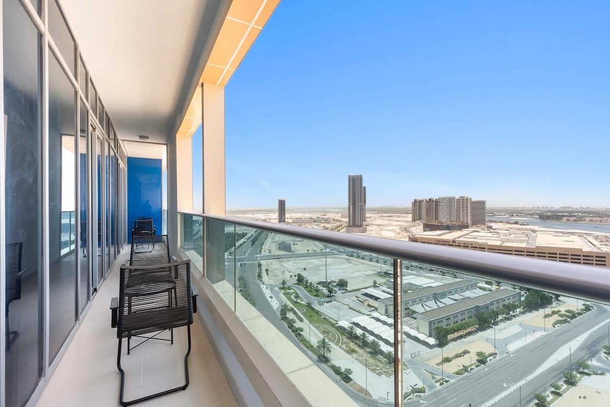Un balcon offrant une vue dégagée sur le paysage urbain, avec notamment des immeubles de grande hauteur et un réseau routier.