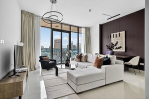 A modern living room with a large window, a sofa, a coffee table, and a TV. - Silkhaus Julphar Tower, Al Reem Abu Dhabi (Abu Dhabi)