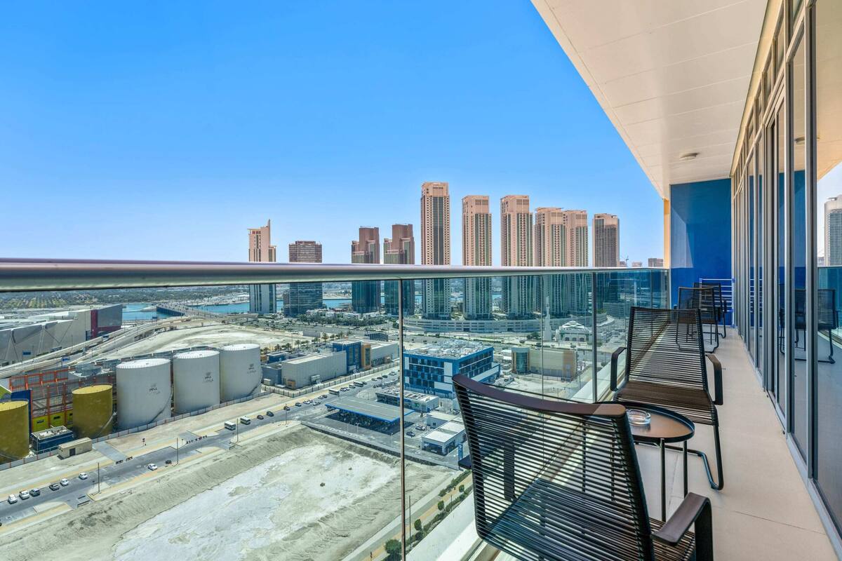 Un balcon offrant une vue sur le paysage urbain, avec notamment des immeubles de grande hauteur et des structures industrielles.