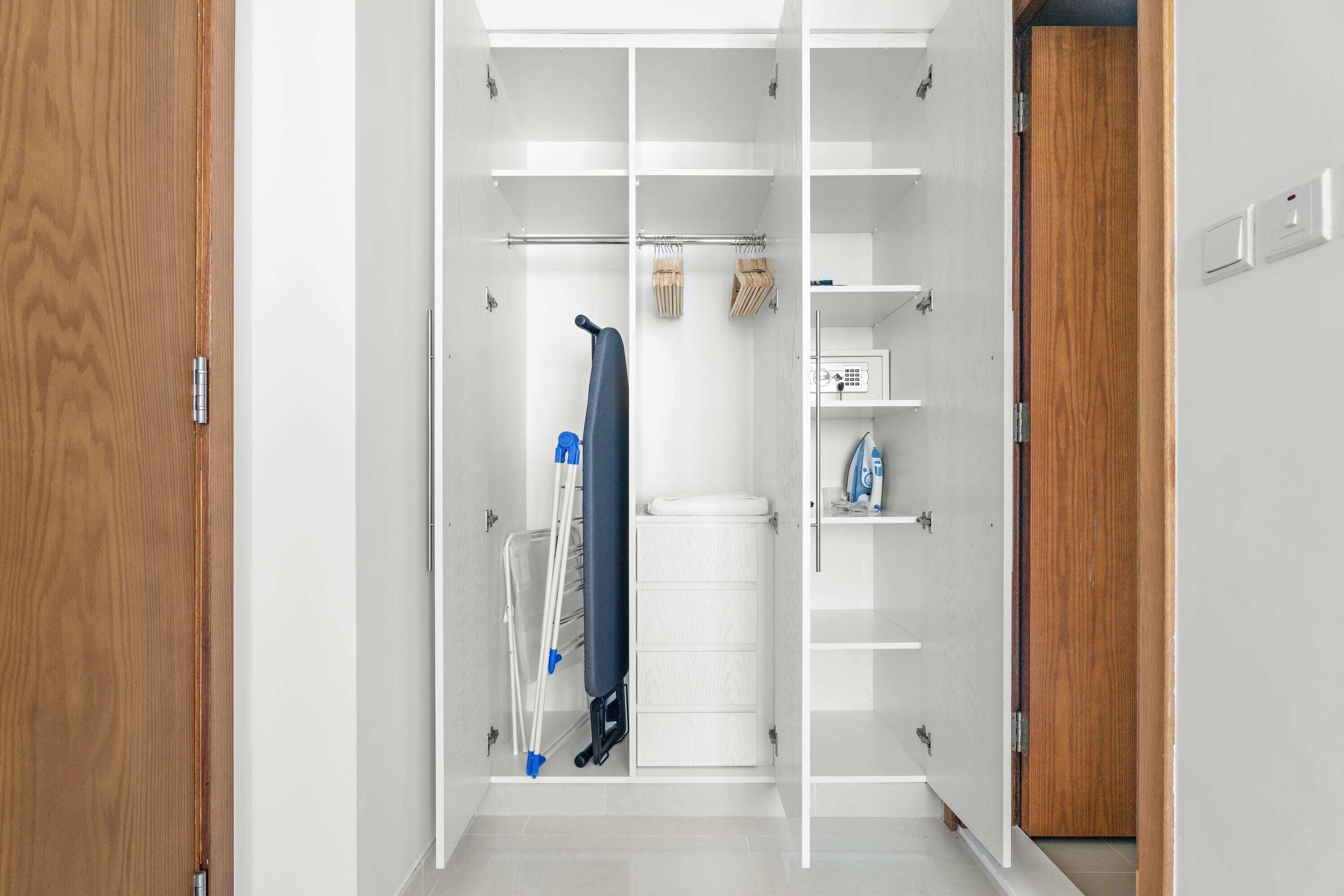 A walk-in closet with a wooden door, a hanging rack, and shelves.