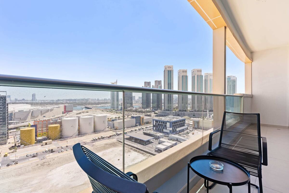 Un balcon offrant une vue sur le paysage urbain, avec notamment des immeubles de grande hauteur et des structures industrielles.