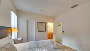 Ein Hotelzimmer mit einem großen Bett, einem Nachttisch mit Lampe, einer Tür und einem Spiegel an der Wand.