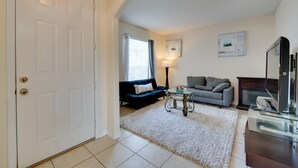 Ein Wohnzimmer mit weißer Tür, einer Couch, einem Couchtisch und einem Kamin.