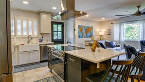 Une cuisine moderne avec des meubles blancs, une cuisinière en acier inoxydable et un coin repas comprenant une table et des chaises.