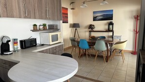 A compact kitchen with a dining area, featuring a microwave, toaster, and coffee maker on the counter.