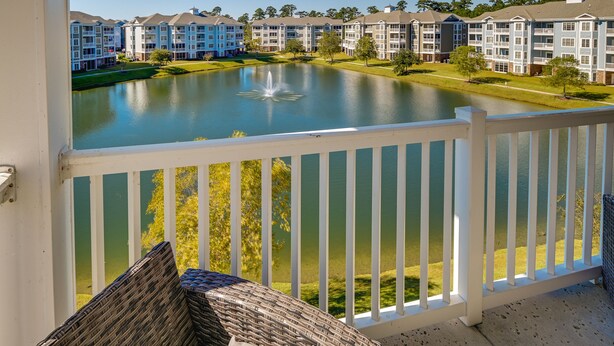 A balcony with a view of a lake, surrounded by multi-story buildings with balconies. - Pool Access & Balcony: Modern Myrtle Beach Condo (Myrtle Beach)