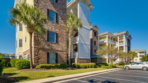 A multi-story building with a brick facade, balconies, and a parking lot. - Pool Access & Balcony: Modern Myrtle Beach Condo (Myrtle Beach)