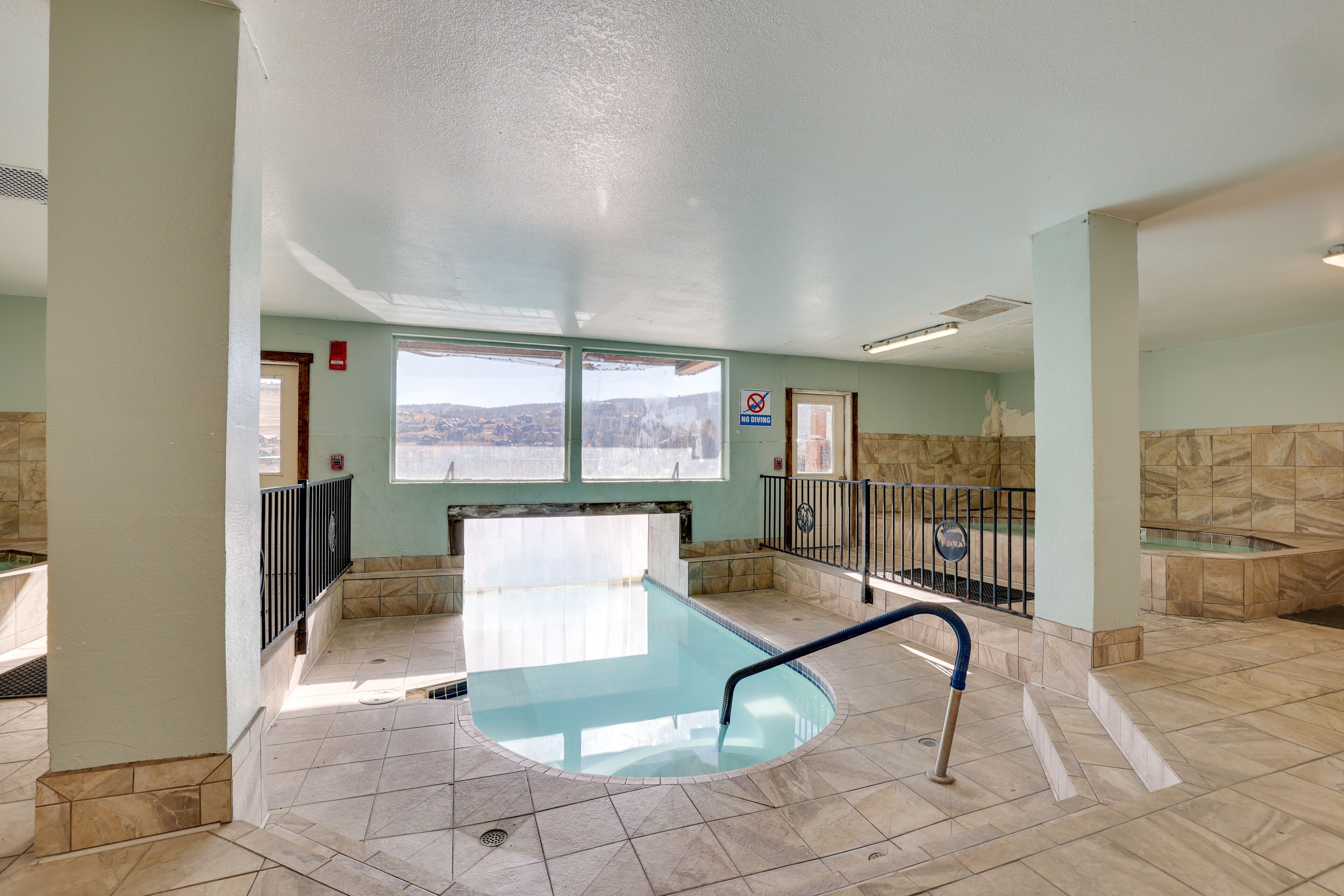 Une piscine offrant une vue sur un paysage montagneux grâce à de grandes baies vitrées.