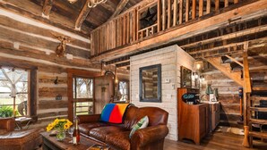 L’intérieur d’un chalet rustique, avec un escalier en bois, des meubles en cuir et une cheminée.