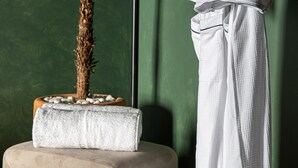 Zona de spa con una planta de palma, una toalla y un taburete de madera.
