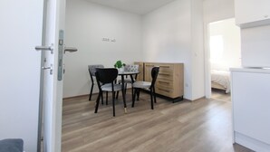 A small, well-lit room with a wooden floor, a dining table with chairs, a small cabinet, and a bed in the corner. - 1 bdr Apt, Kupres, centar, beautiful and uniqe plase (Kupres)