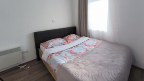 A bedroom with a bed, a radiator, and a window with curtains. - 1 bdr Apt, Kupres, centar, beautiful and uniqe plase (Kupres)