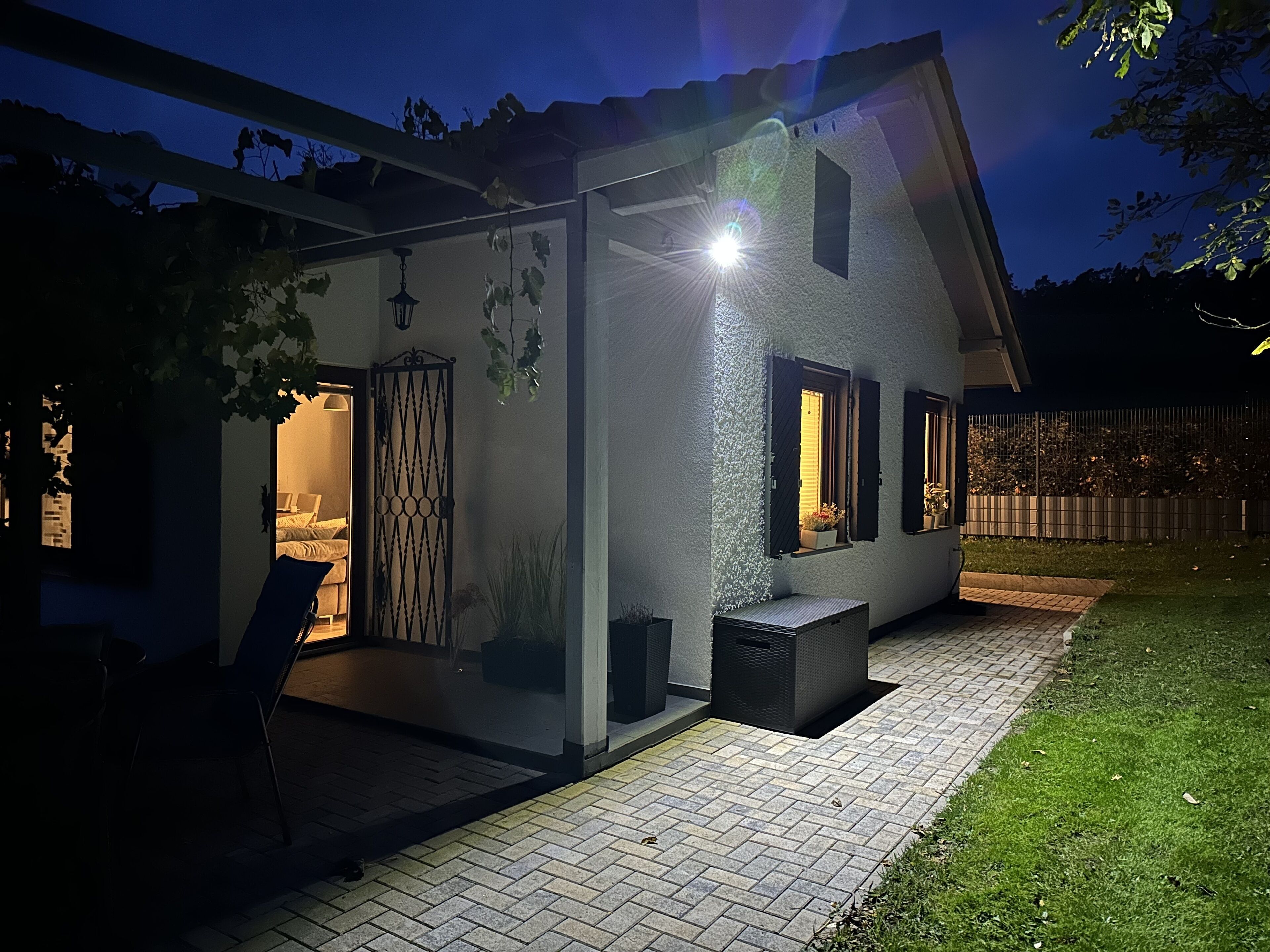 A modern house with a covered patio, a visible bedroom, and a garden area.