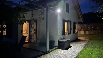 A modern house with a covered patio, a visible bedroom, and a garden area.