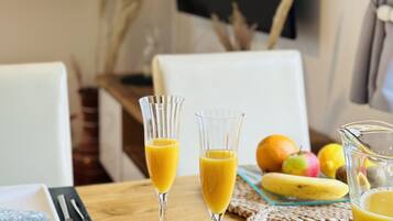 A dining table with two glasses of orange juice, a plate with a blue dessert, and a pitcher of orange juice.