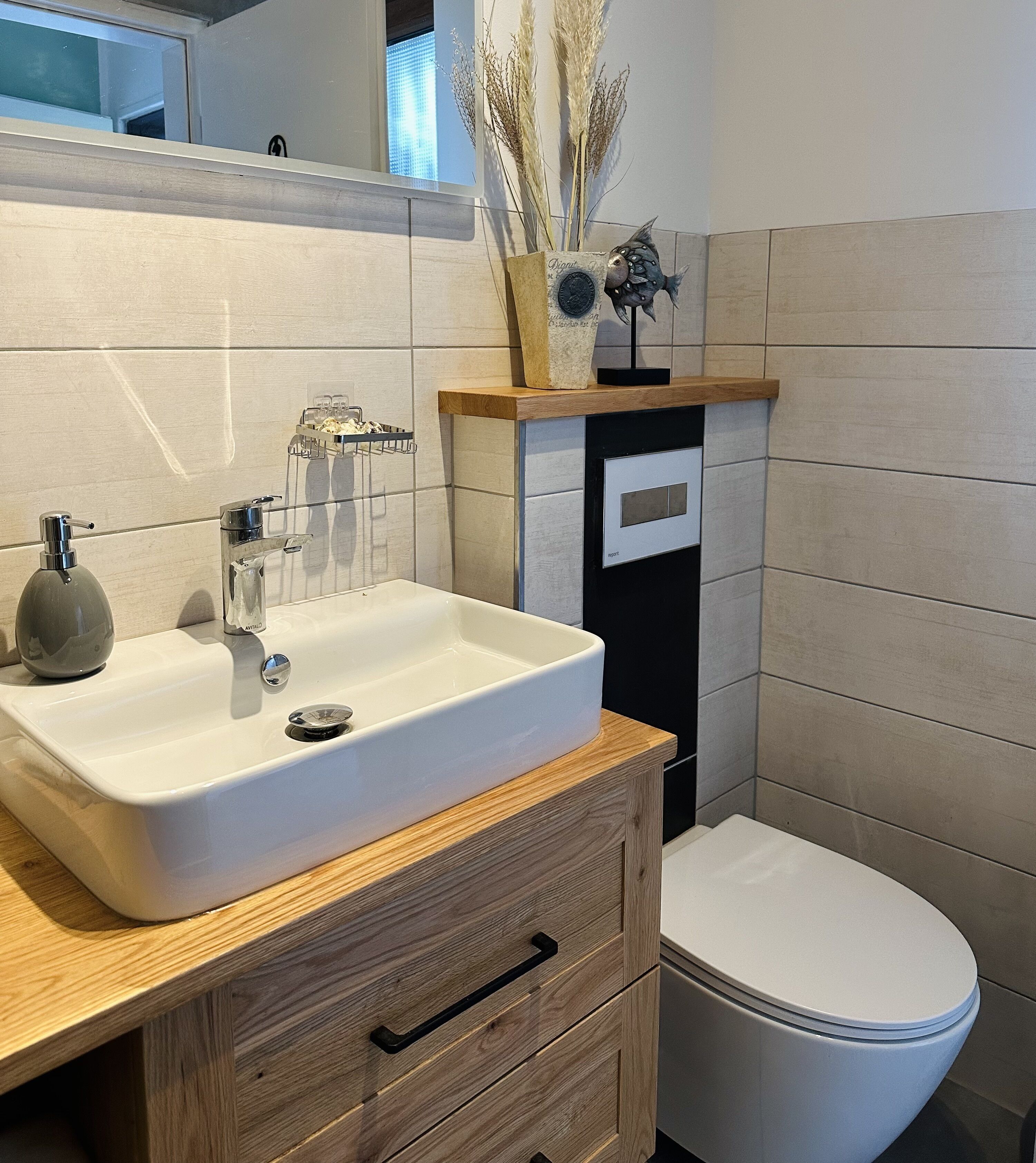 A bathroom with a white sink, wooden vanity, and a toilet.