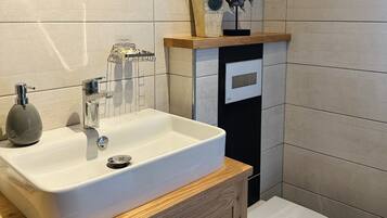 A bathroom with a white sink, wooden vanity, and a toilet.