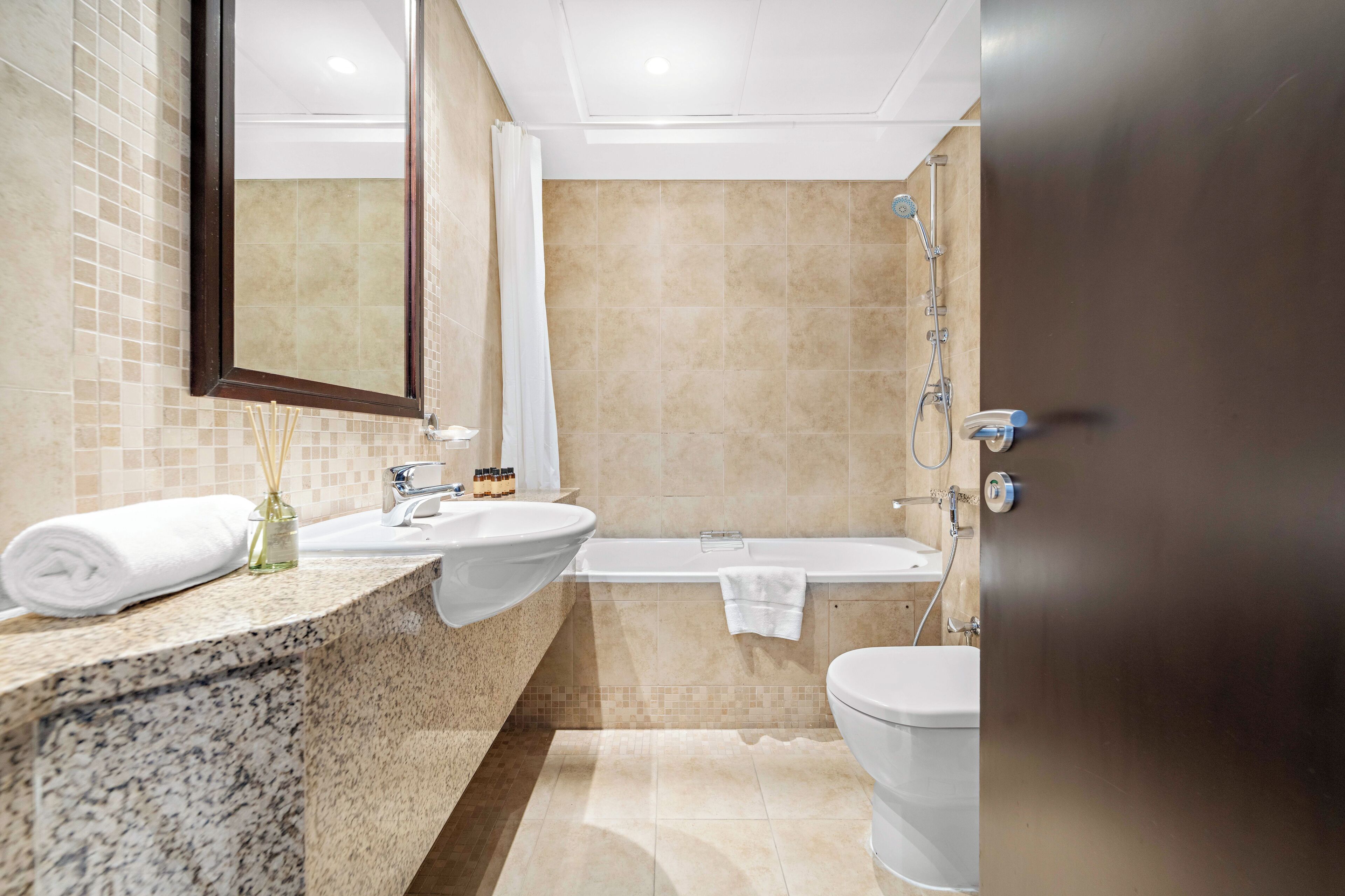 Une salle de bain moderne avec un comptoir en granit, deux lavabos, une baignoire et des toilettes.