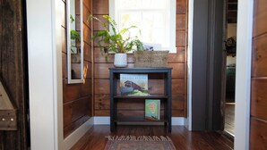 Interior de madera con una consola oscura de madera, una planta en maceta, un cartel de bienvenida y un libro titulado 'Covered Bridges'.