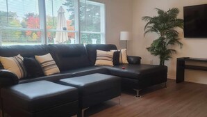 A living room with a sectional sofa, a TV mounted on the wall, a plant, and a console table.