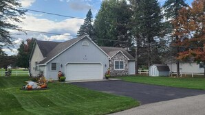A single-story house with a garage, a stone extension, and a well-maintained lawn.