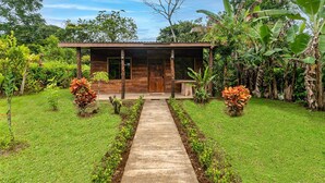 A modern wooden house with a concrete pathway leading to the entrance. - Charming, beautiful cabin. (La Fortuna)
