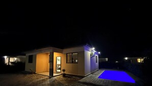 Una casa moderna con piscina por la noche.