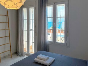A bedroom with a bed, a wooden ladder, and a view of the sea through large windows. - Spectacular House. Ocean Vistas (Benalmádena)