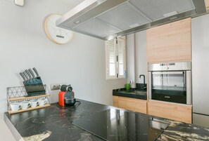 Une cuisine moderne équipée d’un four Bosch, d’une machine à café et d’une horloge murale.