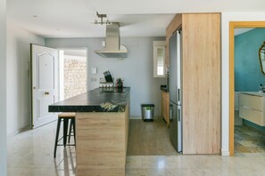 A modern kitchen with a marble countertop, wooden accents, a stainless steel refrigerator, and a stone backsplash. - Spectacular House. Ocean Vistas (Benalmádena)