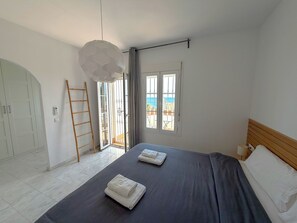 Une chambre à coucher avec un lit, deux serviettes, une tête de lit en bois, une fenêtre donnant sur un paysage agréable, une porte et une échelle.