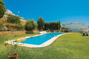 Piscina com muro de pedra e área gramada.