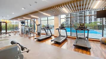Academia moderna com esteiras, aparelhos de musculação e uma grande janela com vista para uma piscina.