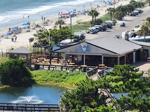 A beachside restaurant with outdoor seating, a pool, and a view of the beach and ocean.