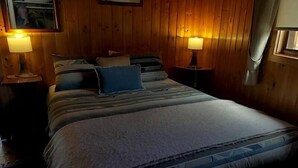 Un dormitorio acogedor con una cama grande, dos lámparas de noche y paneles de madera.