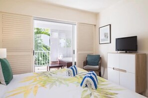 Una camera d'albergo con un letto, una televisione, una sedia, una scrivania e un balcone con vista sul verde.