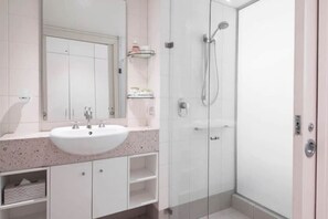 Un bagno con lavandino bianco, specchio e cabina doccia in vetro.