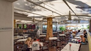 An outdoor dining area with tables and chairs, a large tree, and a sign that reads 'LIME & PEPPER'.