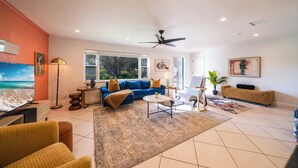 Uma sala de estar espaçosa com um sofá azul, uma mesa de centro e um ventilador de teto.