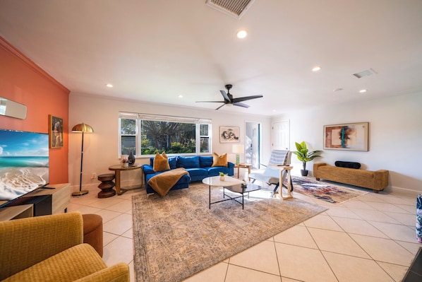 A spacious living room with a blue sofa, a coffee table, and a ceiling fan.