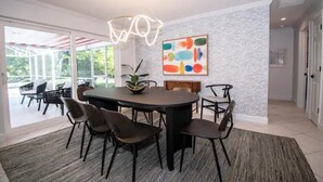 Uma sala de jantar com uma mesa redonda, cadeiras e um lustre moderno.